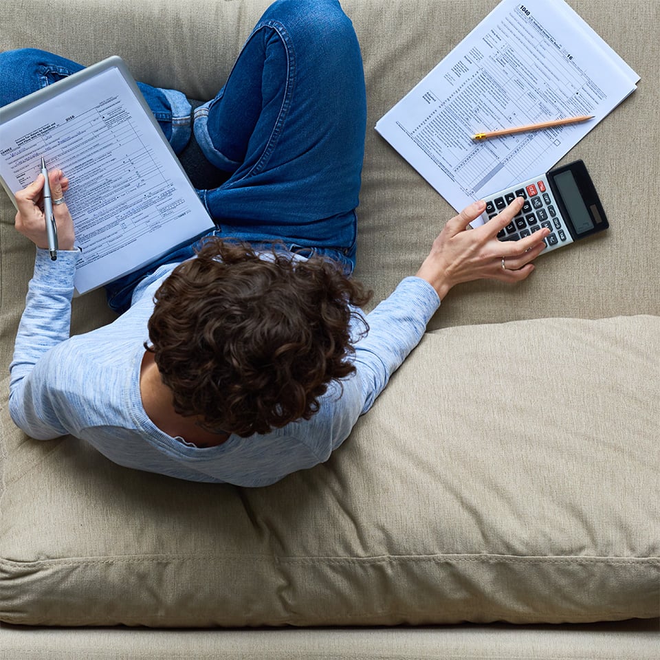 Overhead view of a person doing their taxes while sitting on a sofa