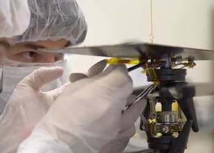 Two masked and gloved scientists examining the helicopter