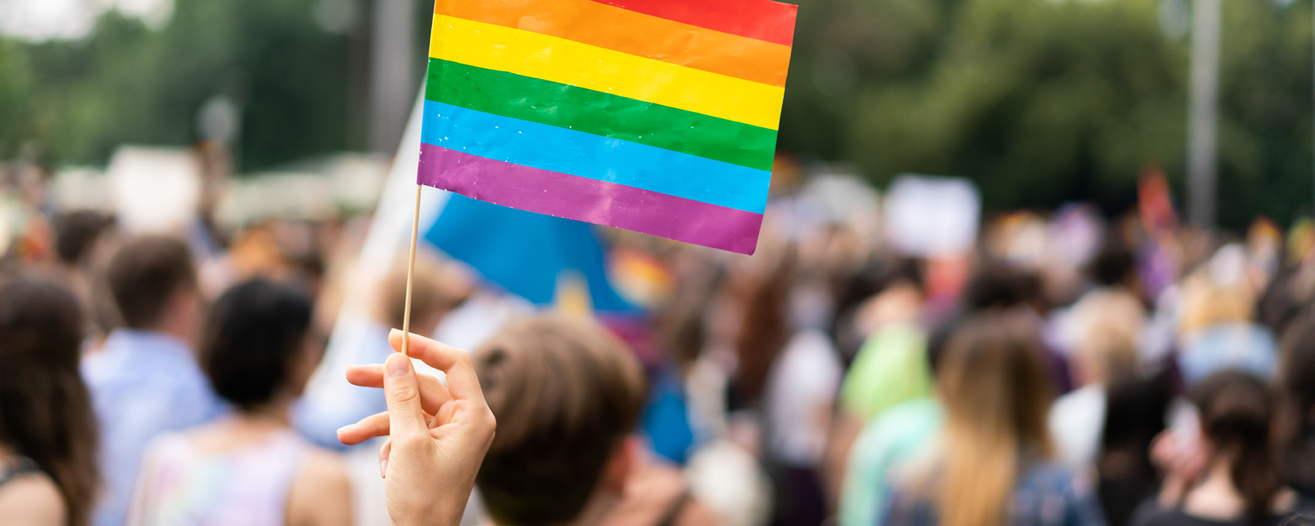 Rainbow flag at pride parade with blurred participants in the background