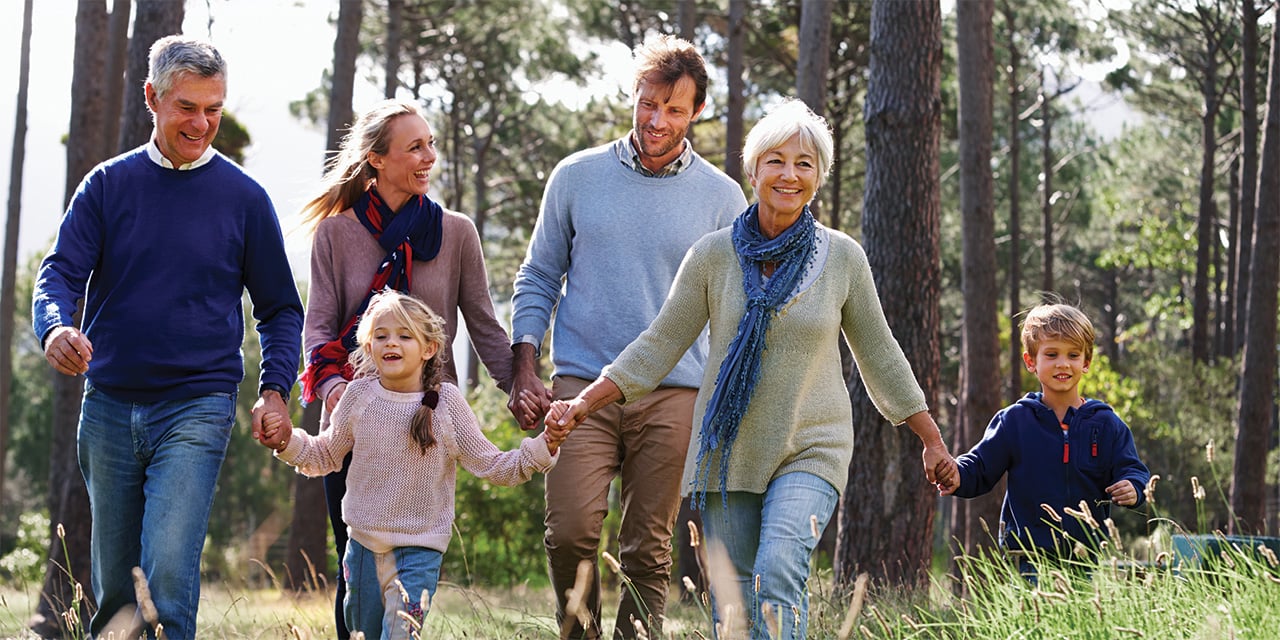 A multi-generational family holding hands while walking through a field
