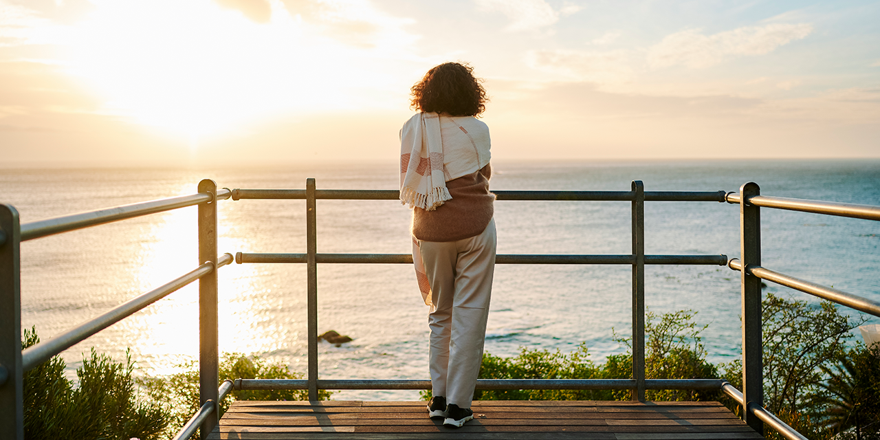 Woman standing along on pier looking at a body of water