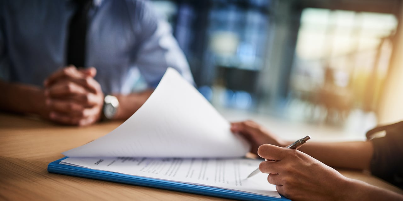 Advisor and client review and sign financial planning documents across a conference table.