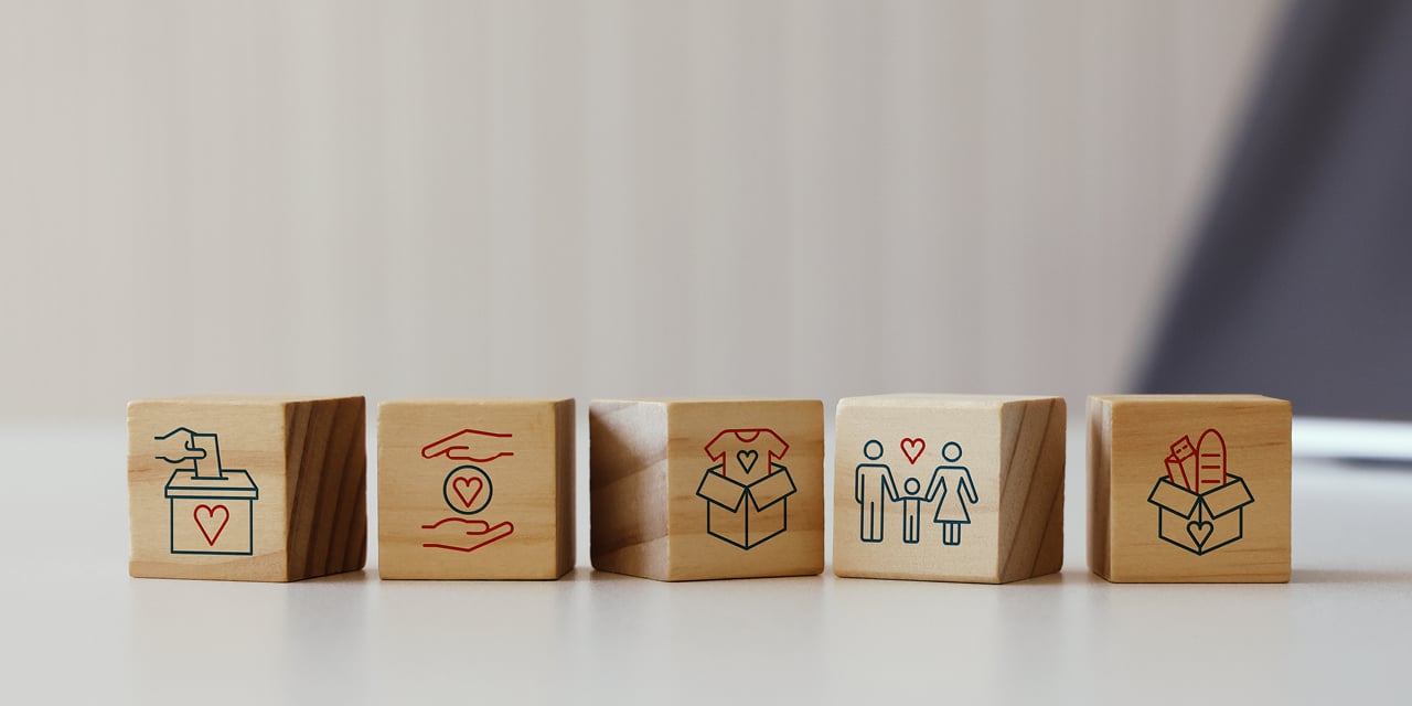 Five wooden blocks with icons of care, heart, family and gift, symbolizing financial protection and customer support.