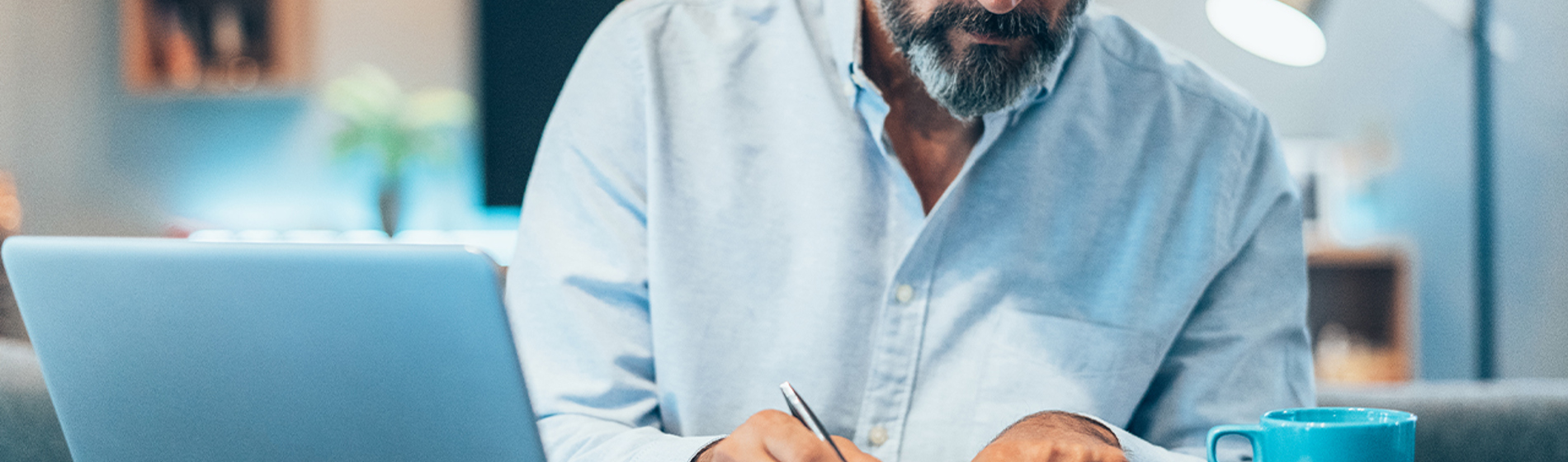 A man reviews papers as he sits at a desk with a computer.