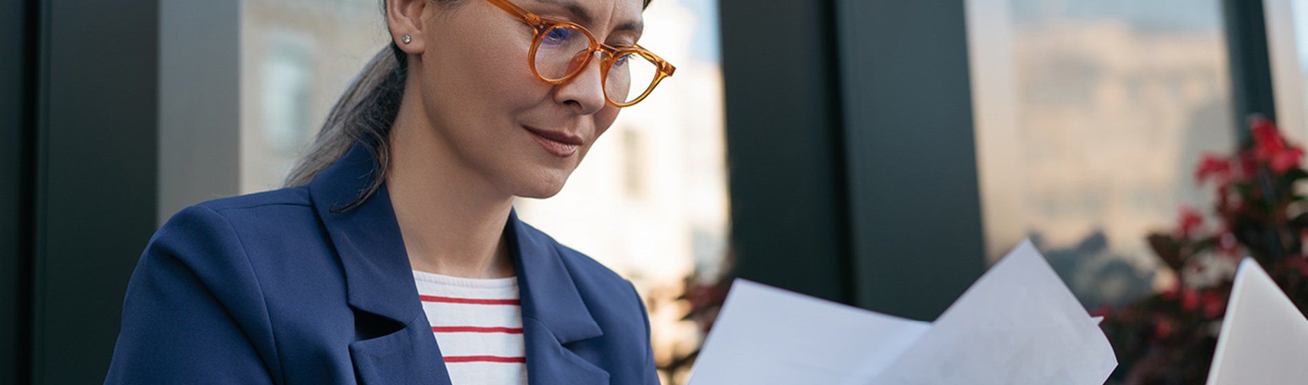 Woman wearing red glasses looking at paperwork.