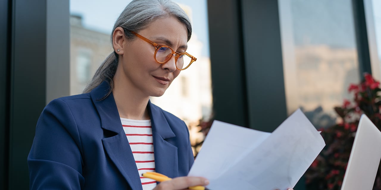 Woman wearing red glasses looking at paperwork.