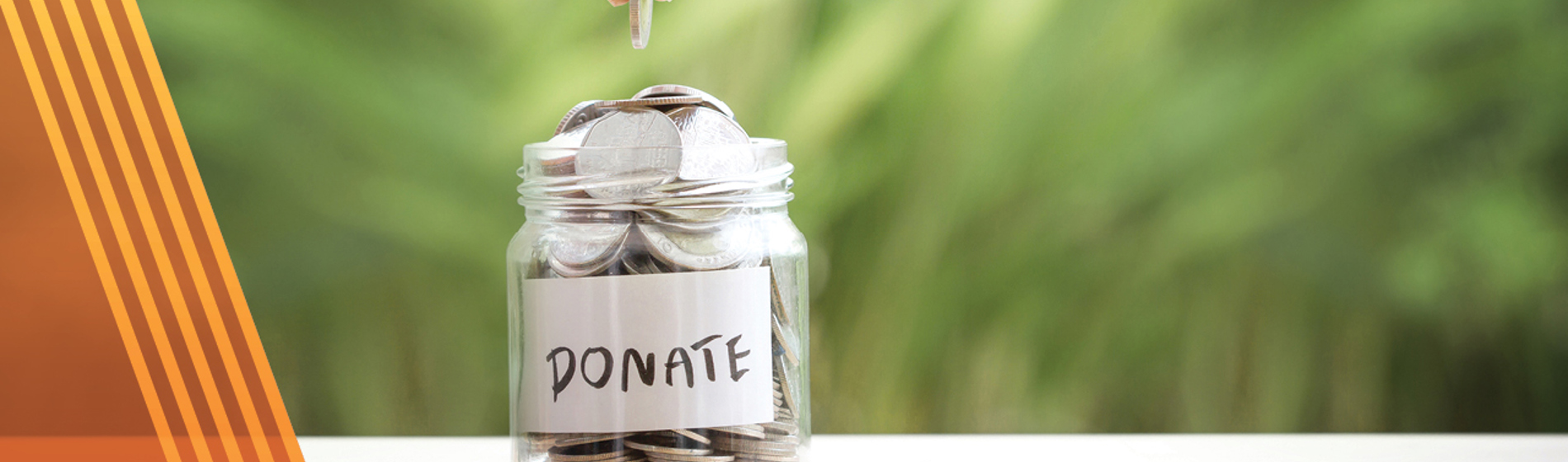 Hand dropping coins into a jar with the words donate on the front.