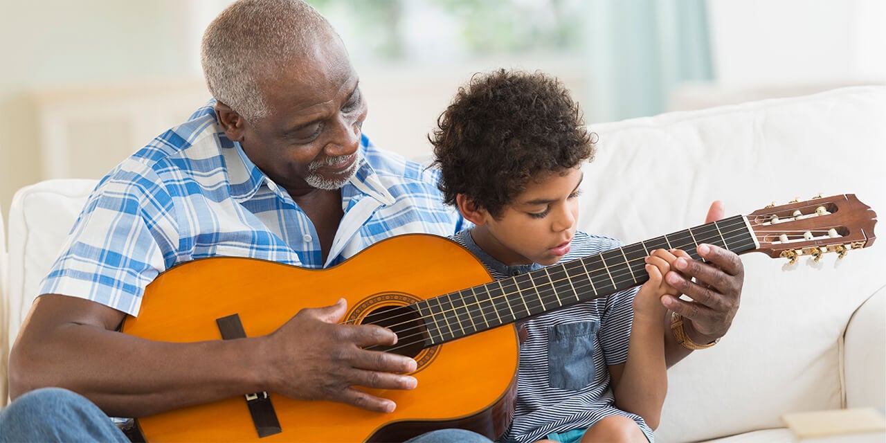 Grandpa teaching grandson to play the guitar.