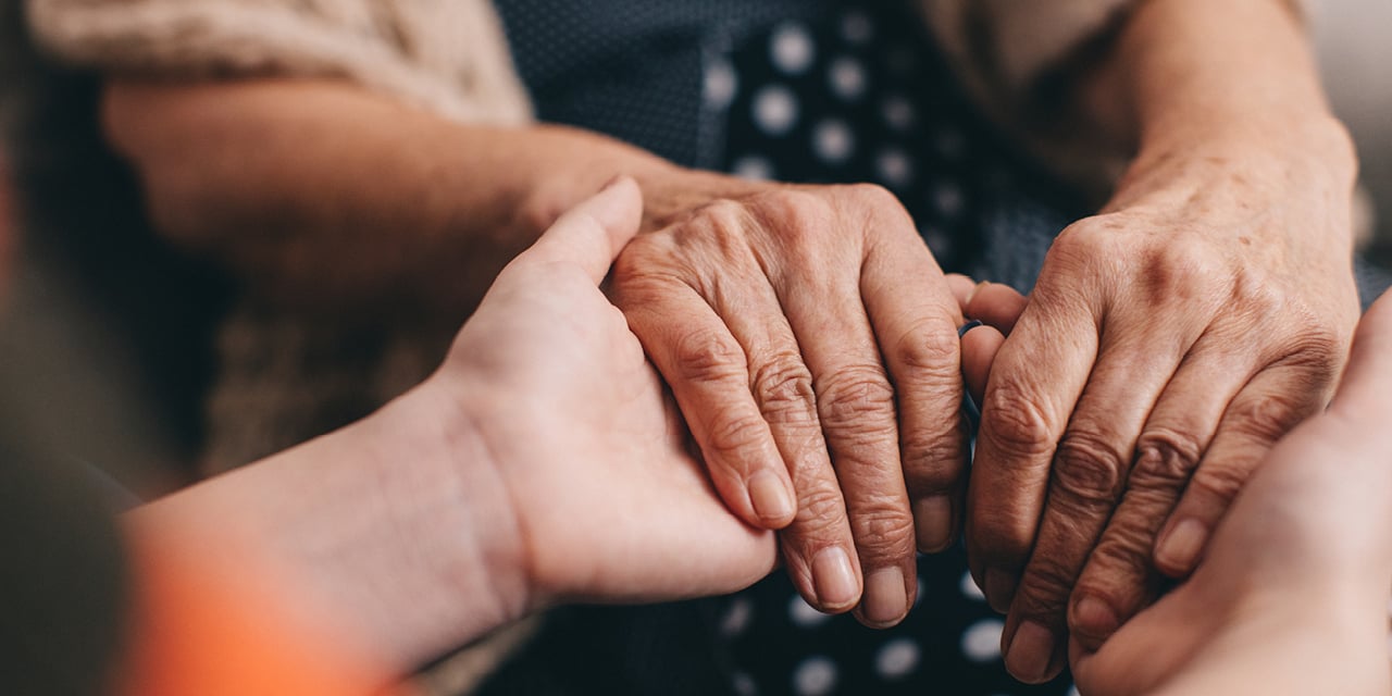 Elderly woman holding hands with youger person