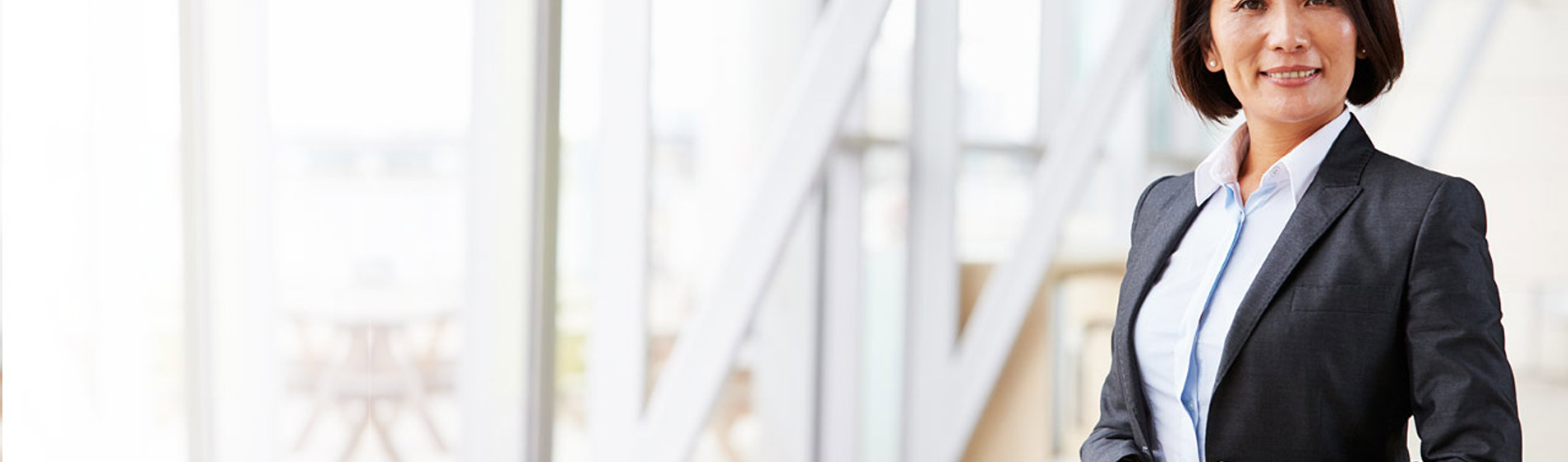 Professional woman is a suit standing next to a window.