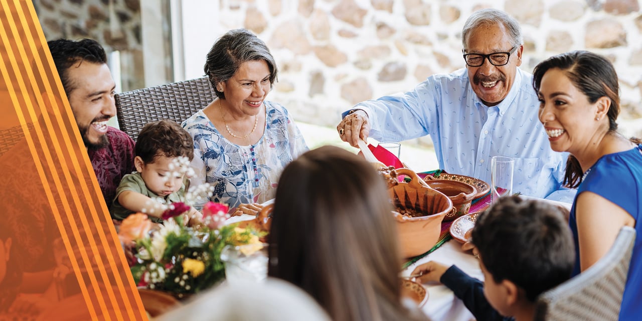 Multigenerational family eating together ad a dining room table.