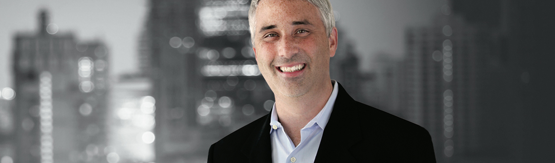 Mike Antonelli stands in front of a black and white cityscape