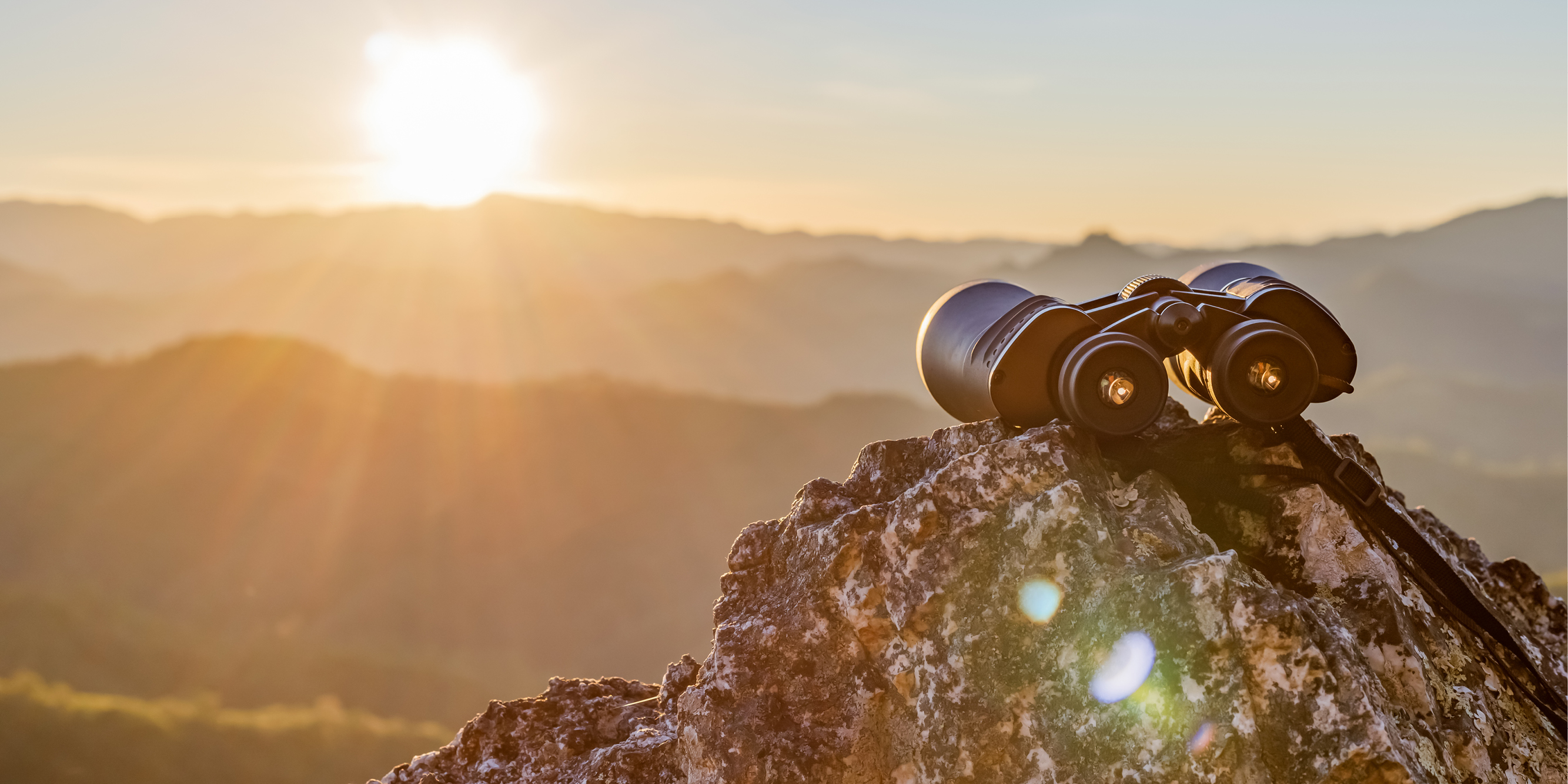 Binoculars on a rock at sunset