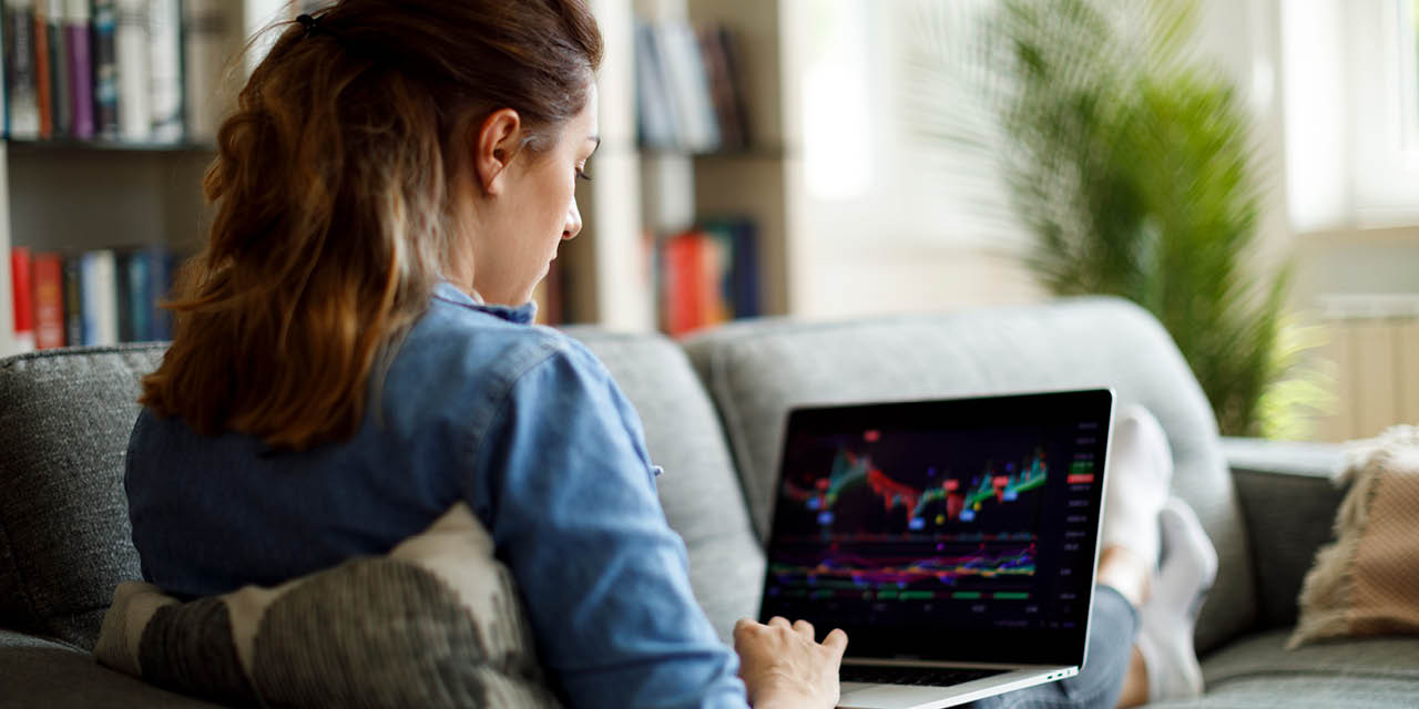A woman reviewing market graphs on a laptop