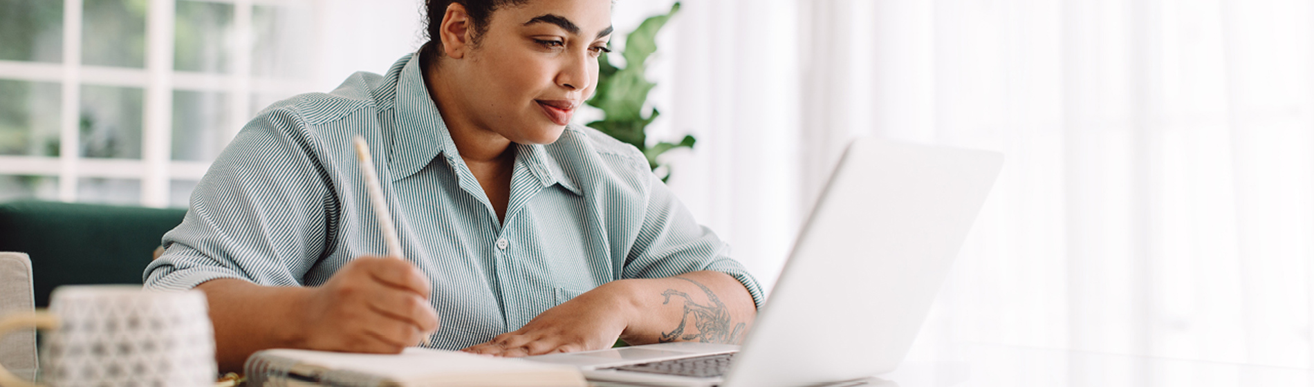 Woman doing paperwork at a computer sitting at a table.