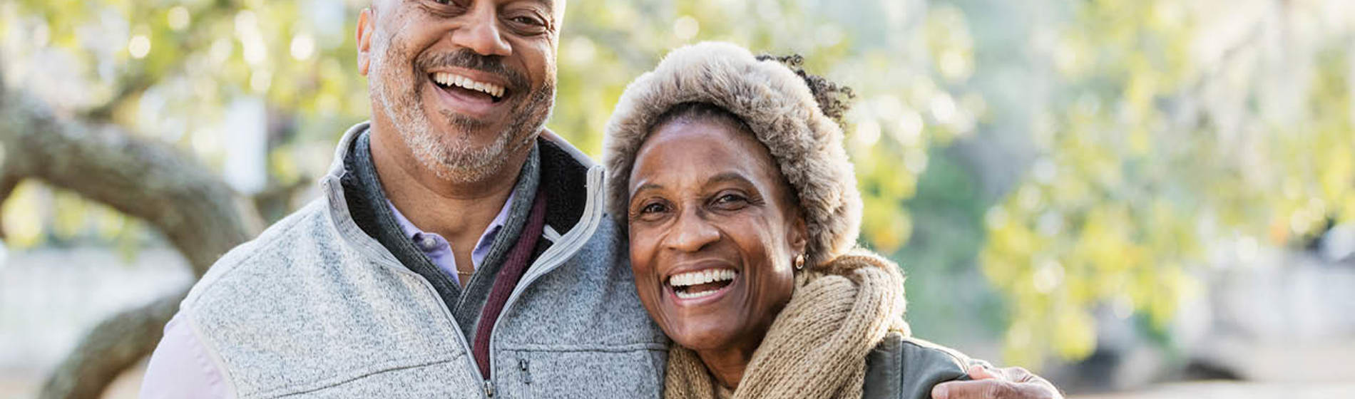 Middle-aged couple smiling while standing in a park.