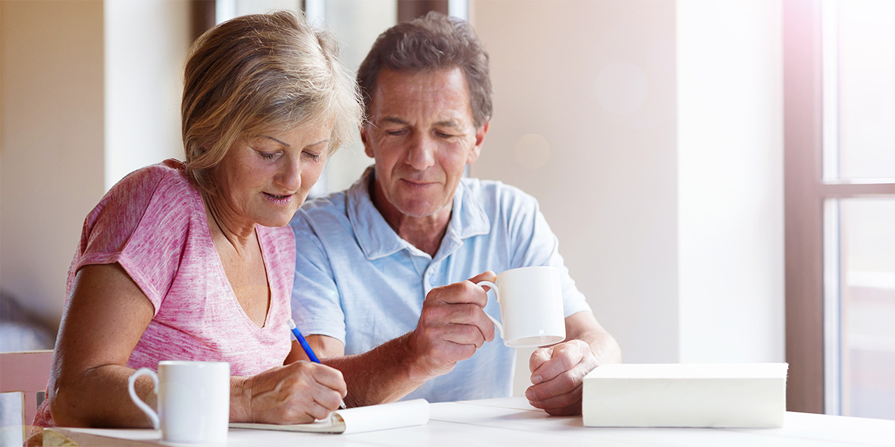Older couple at a table having coffee while revising paperwork