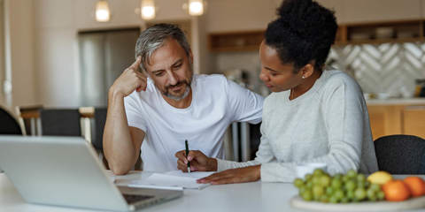 Couple sitting at kitchen table reviewing paperwork.