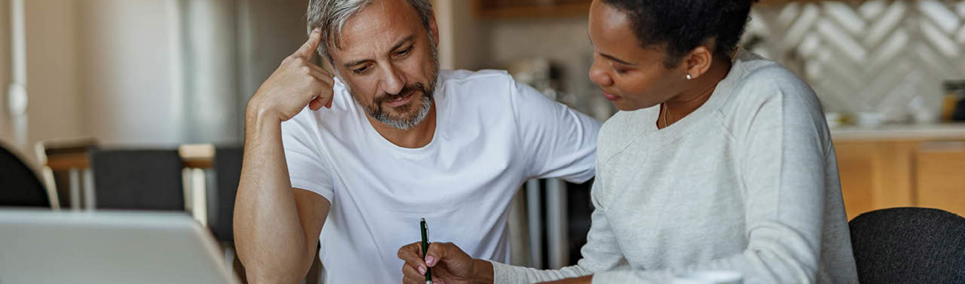 Couple sitting at kitchen table reviewing paperwork.