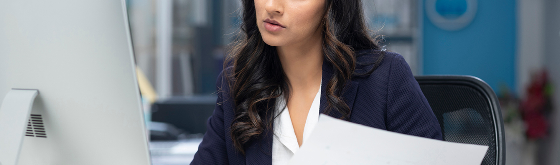 Professional woman reviewing documents while at a computer.