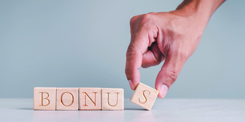 Hand spelling out the word bonus using blocks.