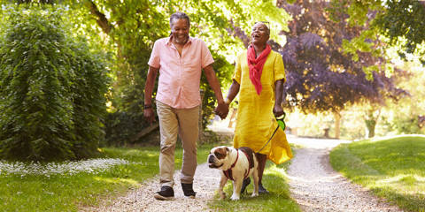 Middle aged couple walking a dog down a gravel path