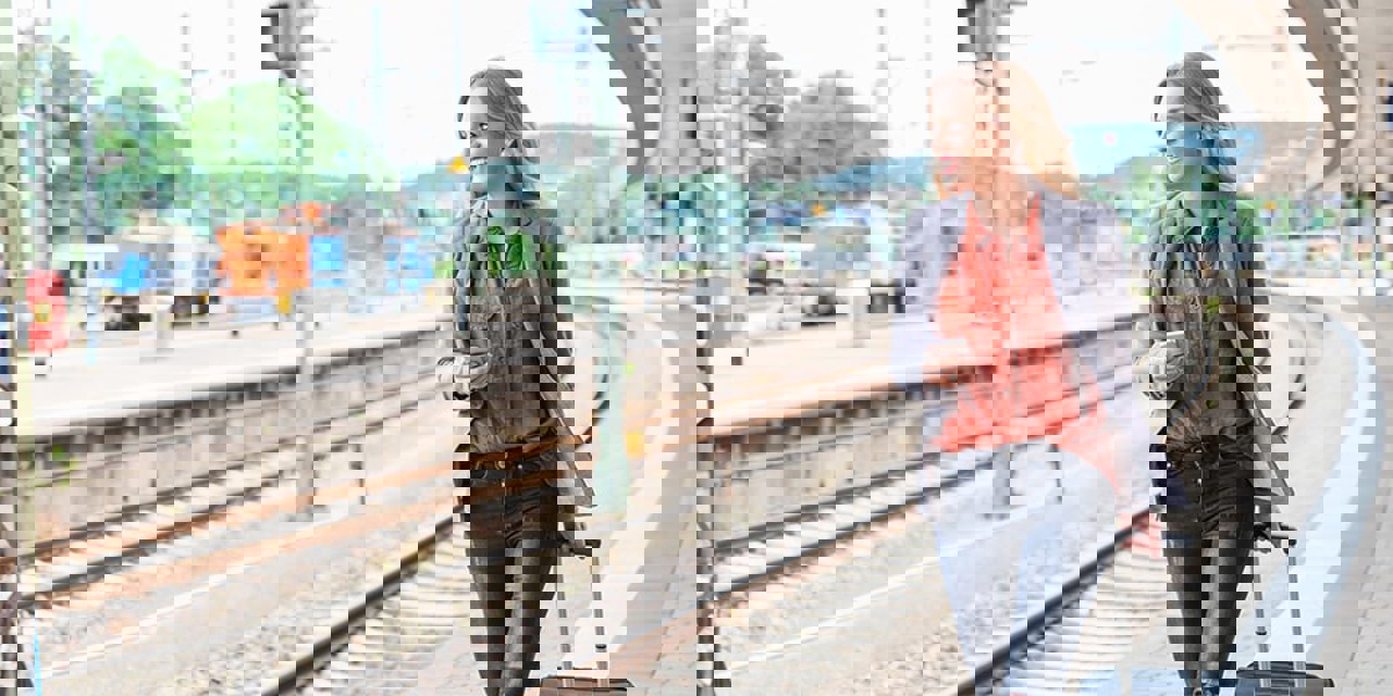 Blonde woman, smiling, while walking along train platform.