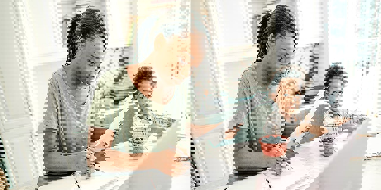 Woman sitting at counter going over documents with young child next to her.