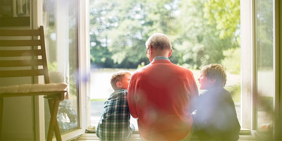 Grandfather sitting with grandchildren in door opening to outside.