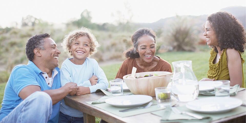 Multi-generational African-American family sitting outside enjoying a meal.