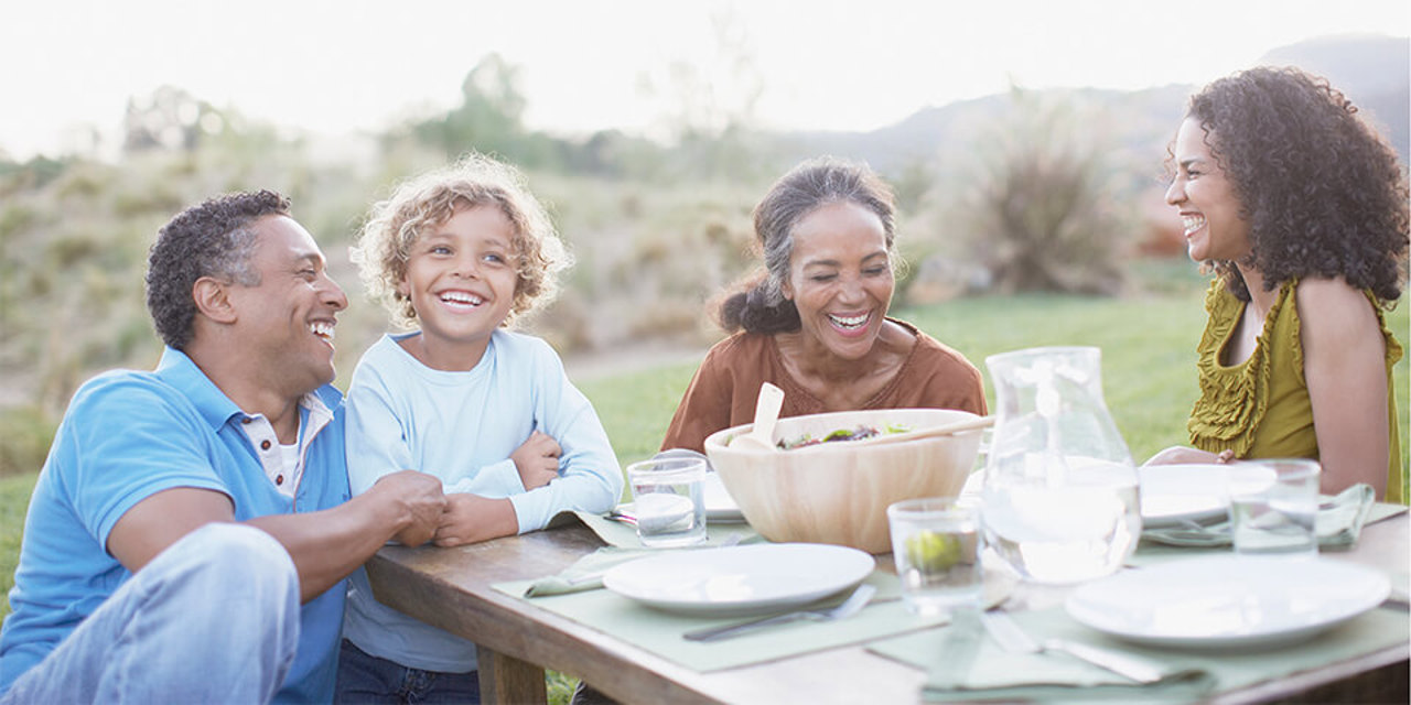 Multi-generational African-American family sitting outside enjoying a meal.