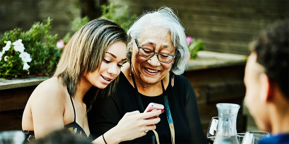 Grandmother and granddaughter looking at a phone's screen.