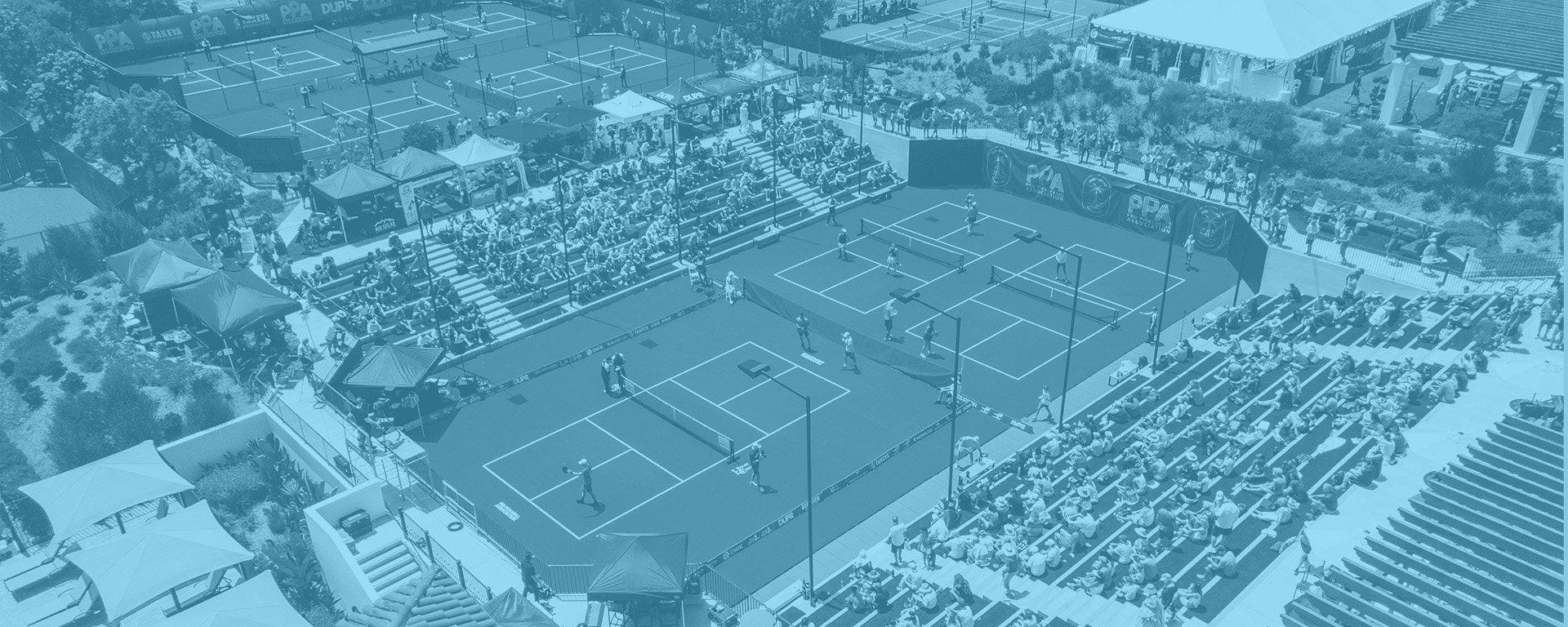 Blue overlay on an aerial image of a pickleball court surrounded by bleachers full of spectators