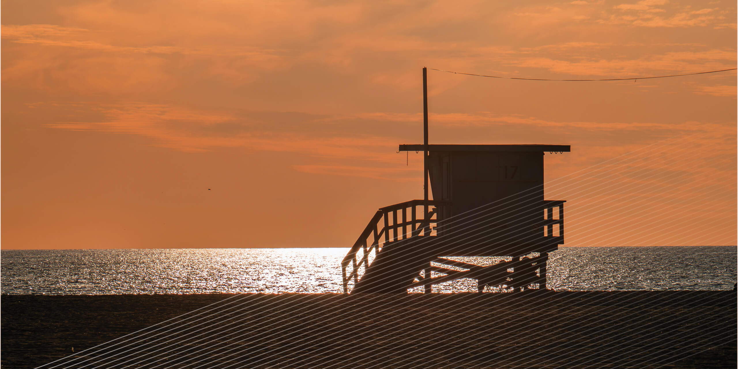 Lifeguard stand on beach at sunset
