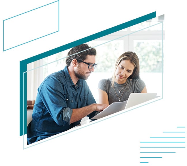 A young couple reviewing documents in their home framed by blue parallelograms in the shape of the Baird logo