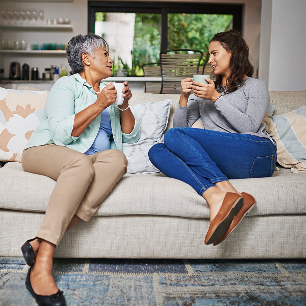 Two women on a couch sharing coffee and conversation