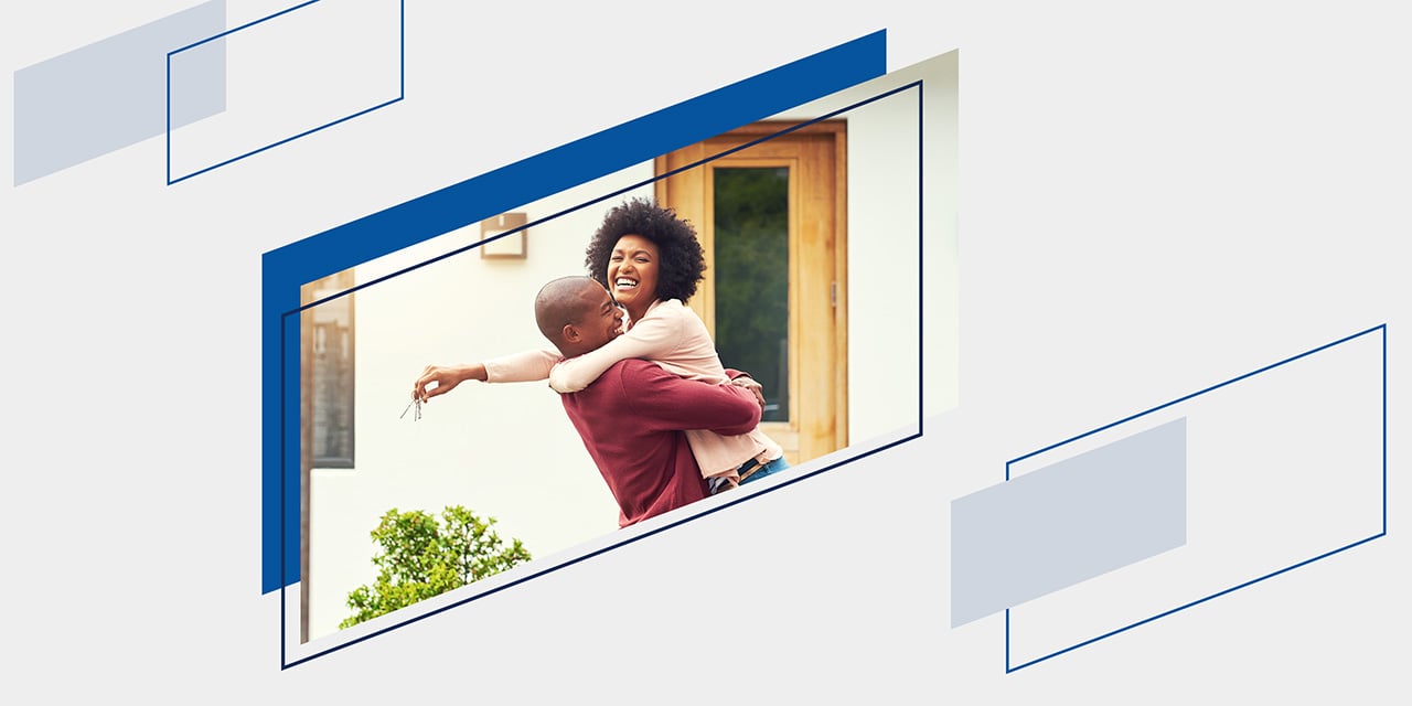 an embracing couple celebrate outside the entryway of their first home
