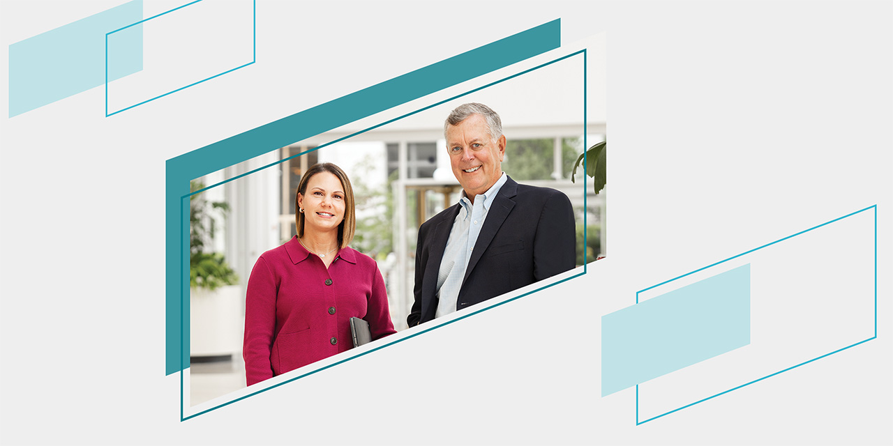 Two professionals standing together in a bright office setting, dressed in business attire