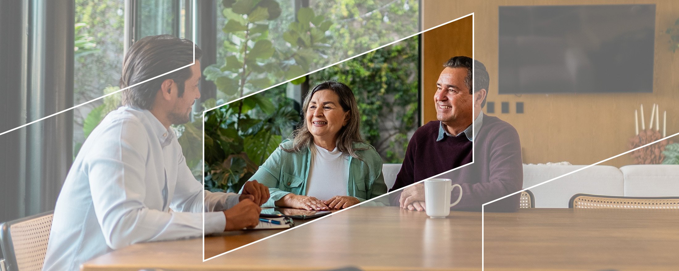 A financial advisor meeting with a couple at wooden table in a modern room with large windows and greenery outside