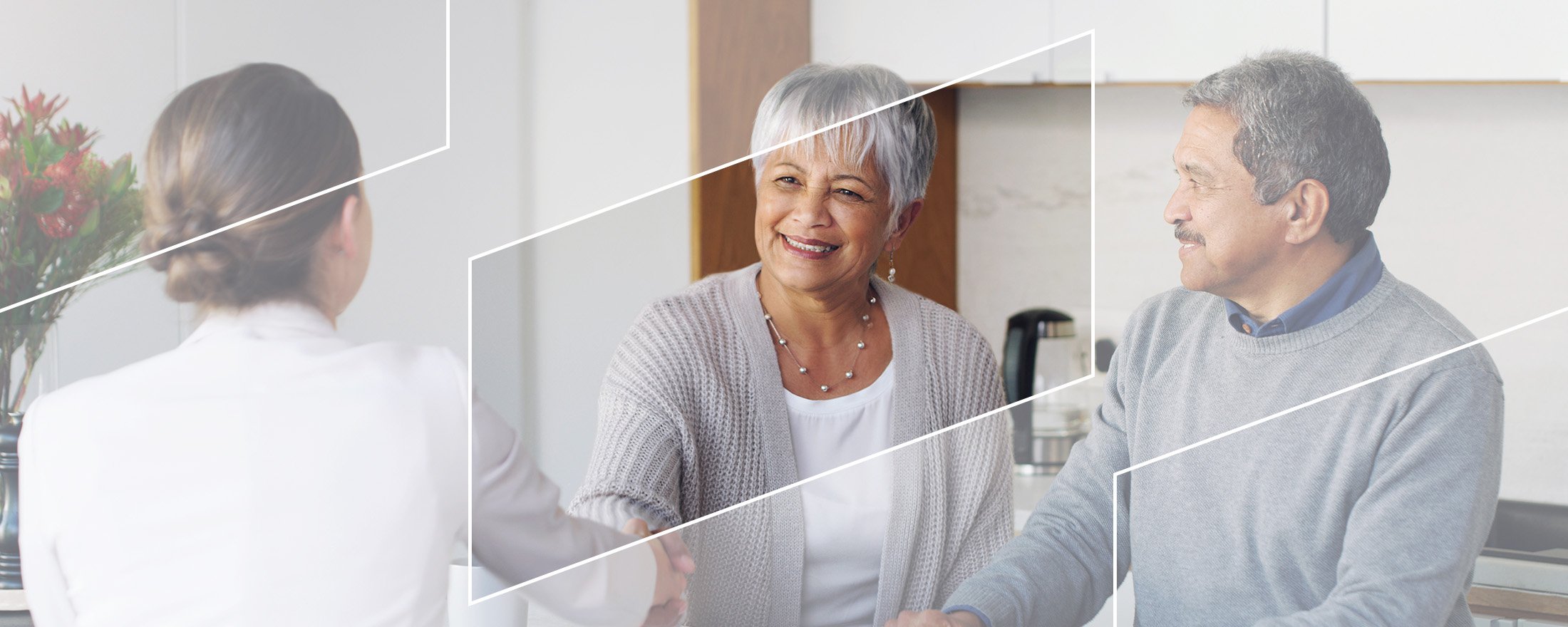 Two people meeting with a financial advisor at a table, shaking hands in a bright modern office setting