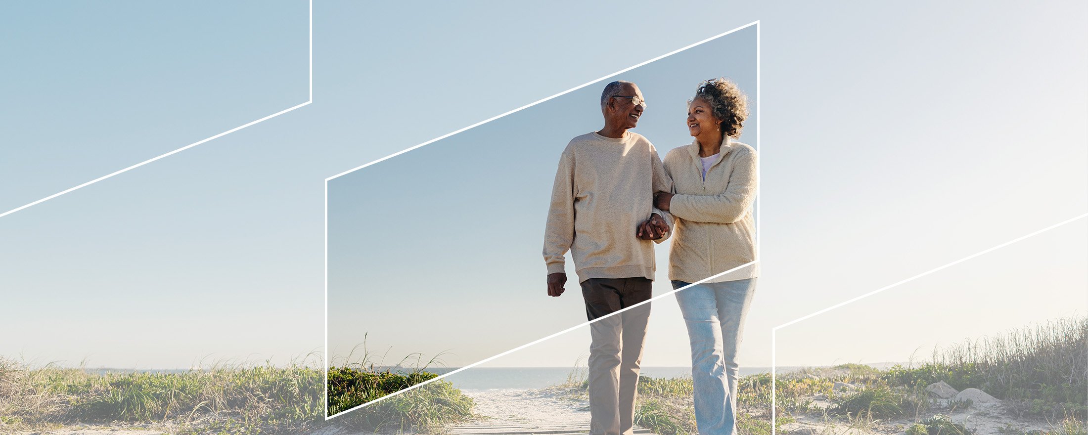 A retired couple walking together along a beach framed in a subtle parallelogram 
