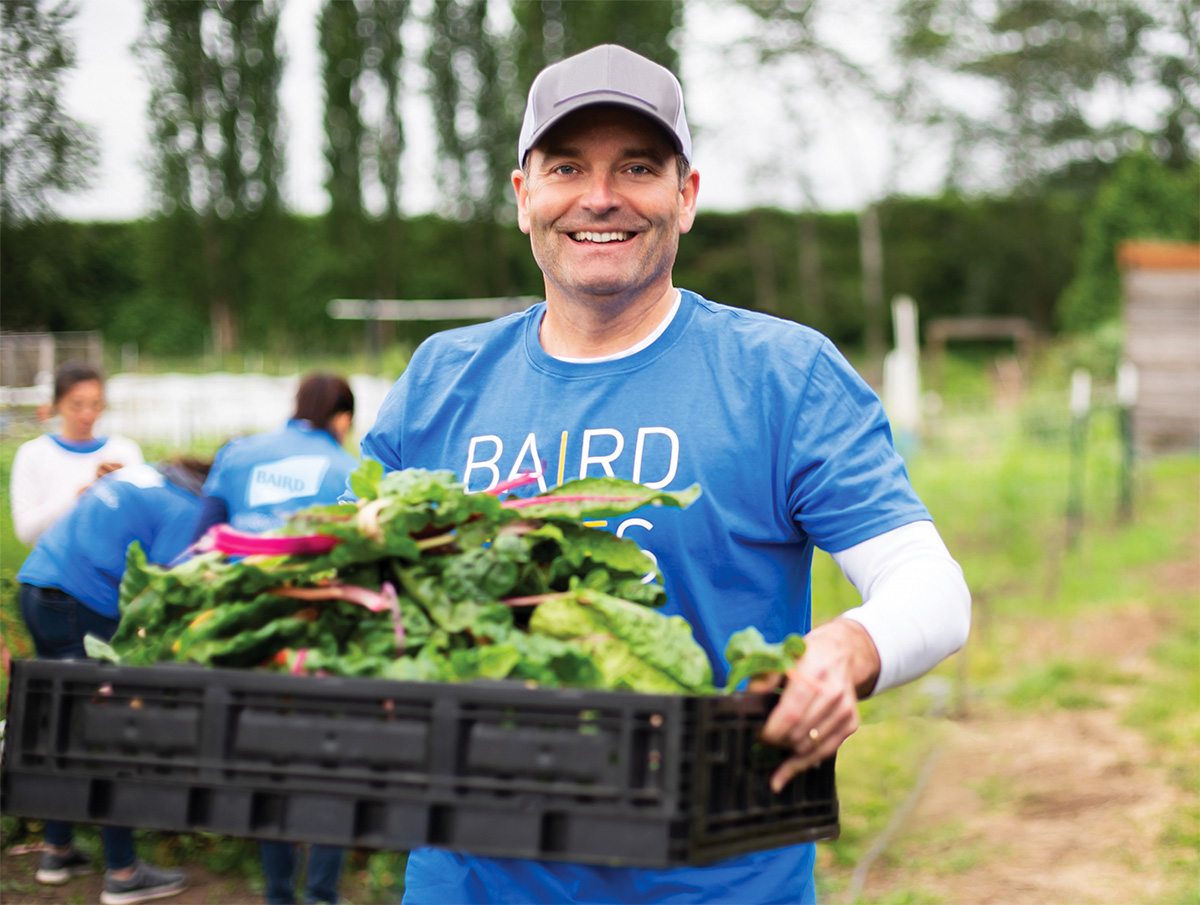 A Baird associate carries a box of greens at a volunteer event