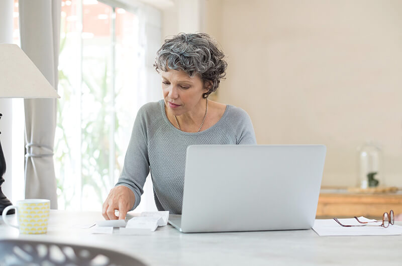 An woman with a laptop, reviewing receipts while using a calculator