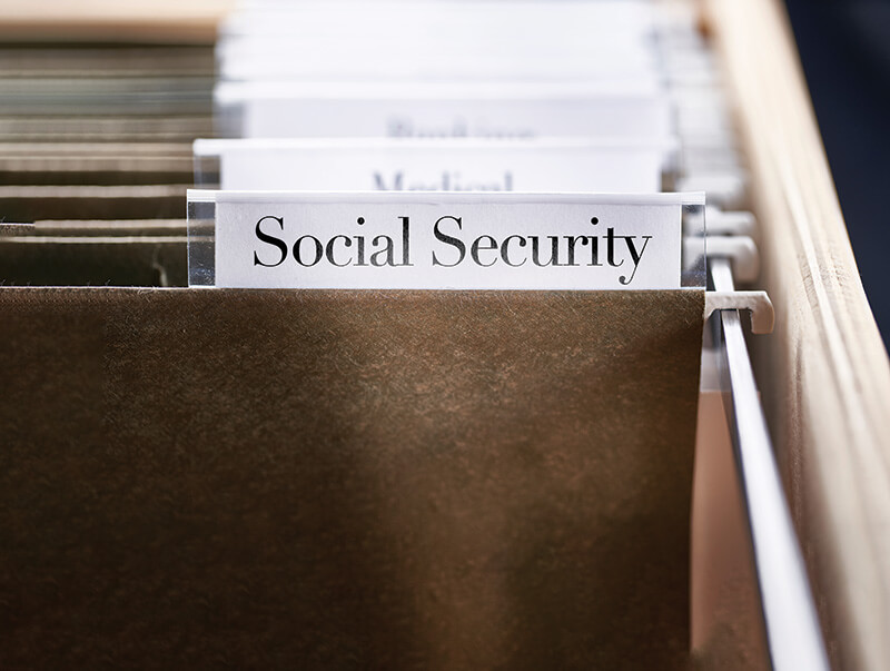 Closeup of a green file folder labeled, "Social Security" in a cabinet